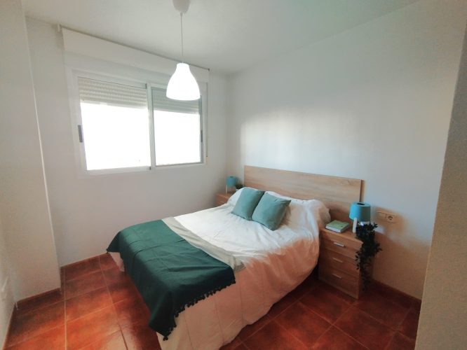 Primer plano del dormitorio principal con una ventana y dos mesitas de noche