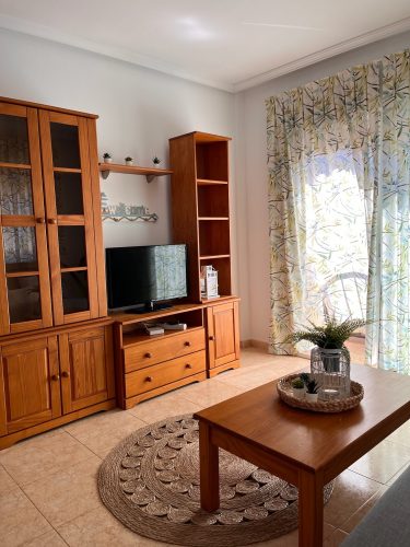 Primer plano del salón con dos armarios, un mueble para televisión, una mesita de noche y un ventanal