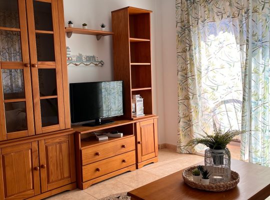 Primer plano del salón con dos armarios, un mueble para televisión, una mesita de noche y un ventanal