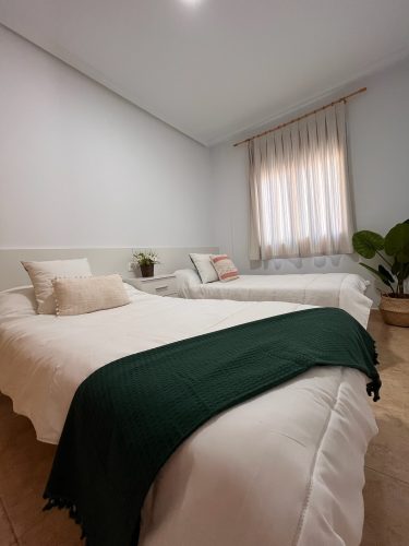 Dormitorio de invitados con dos camas individuales, una ventana y unas mesitas de noche