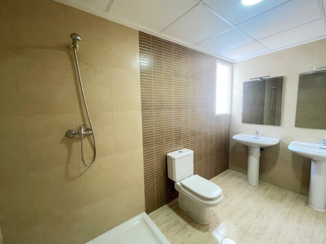 Baño principal de la vivienda con una ducha, dos lavabos, dos espejos y una ventana