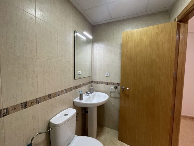 Baño equipado con un retrete, un espejo y un lavabo