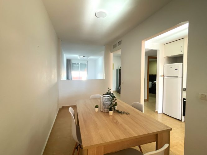 Cuarto plano del salón desde el que se veuna mesa con 4 sillas y la cocina