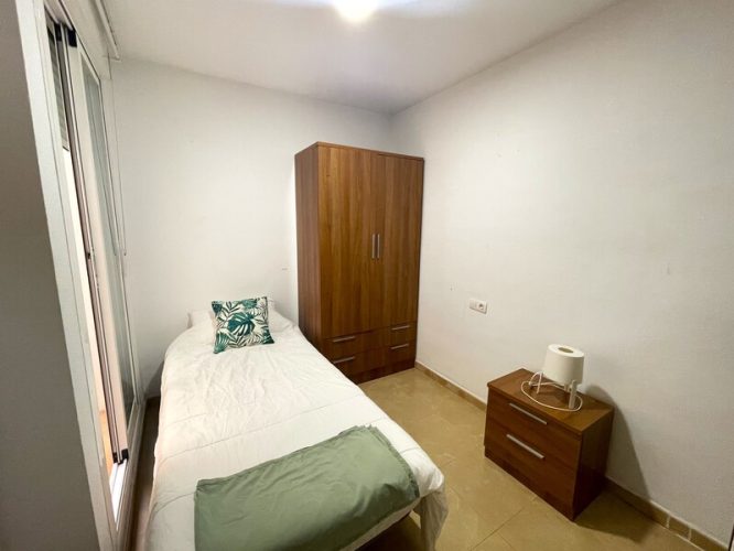 Dormitorio de invitados con una cama individual, un armario y una mesita de noche