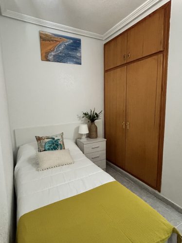 Dormitorio de invitados con una cama individual, un armario empotrado y una mesita de noche