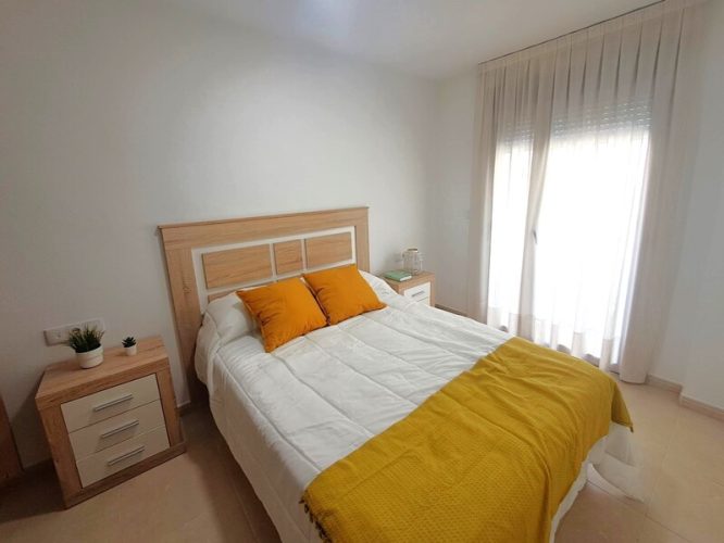 Primer plano del dormitorio con un ventanal y dos mesitas de noche