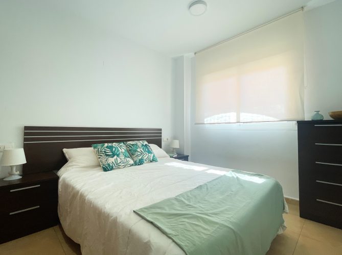 Dormitorio principal con una cama de matrimonio, dos mesitas de noche y una ventana